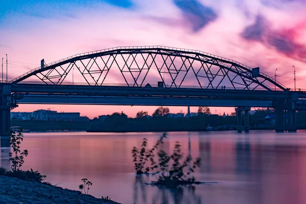 The bridge over the river at sunset. Combined bridge in Tyumen at sunset. Long exposure.