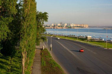 Kasaba sabahın erken saatlerinde. İki araba yollara. Şehrin Nehri yakınında. City road yakınındaki ağaçlar. Parlak kırmızı araba şehir de yol. Sola dön.