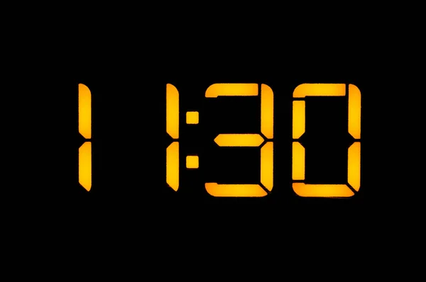 Ηλεκτρονικό ψηφιακό ρολόι με πορτοκαλί αριθμούς σε ένα μαύρο προγρού — Φωτογραφία Αρχείου