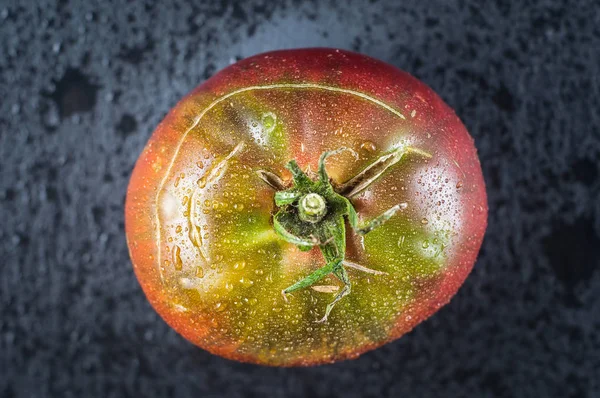 Belle tomate rouge maison mouillée en gouttes sur un fond de pierre noire — Photo