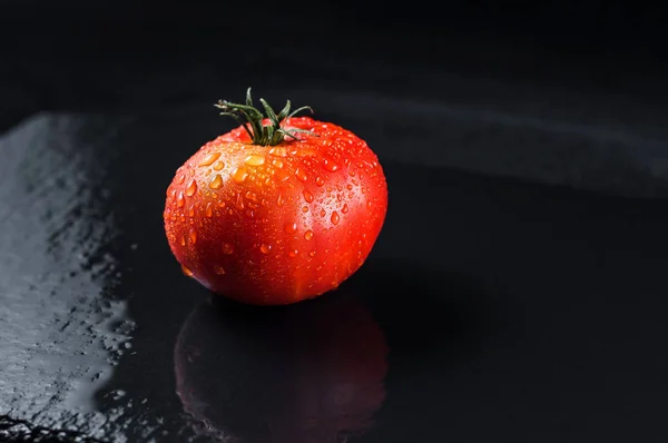Tomate humide rouge vif sur une surface de pierre mouillée en gouttes . — Photo