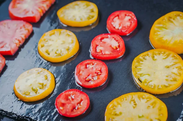 젖은 돌 표면에 빨간색과 노란색 토마토를 슬라이스 — 스톡 사진