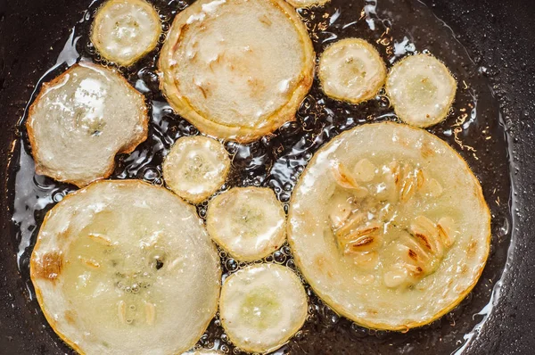Frite a abobrinha fatiada em casa em uma panela no óleo de girassol . — Fotografia de Stock