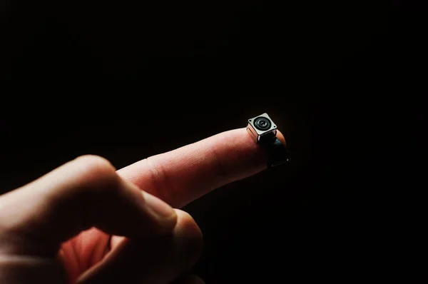 Parmağında bir döngü olan küçük bir kameranın kare modülü.