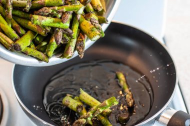 Sprays of sunflower oil when spilling asparagus in a preheated pan