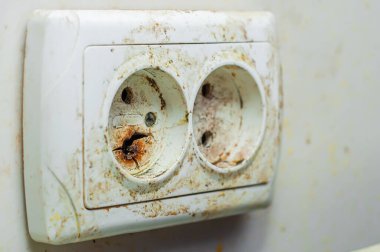 Duvara monte edilmiş plastik priz çok kötü durumda, kirli ve yanmış.