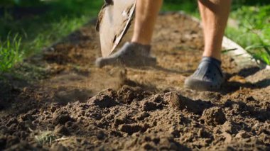 Bir adam sabahın erken saatlerinde bahçe yatağını kürekle kazıyor, yavaş çekimde. Yüksek kaliteli FullHD görüntüler