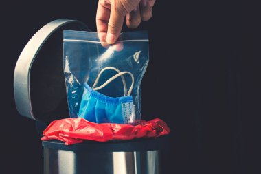 Fermuar torbasında tek kullanımlık tıbbi maskeyi mikrop kapmış çöp kutusuna bırak.