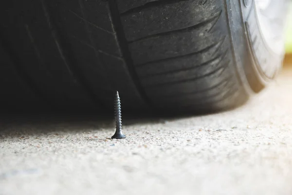 Close up of sharp metal screw on road nearly to puncture a car tire