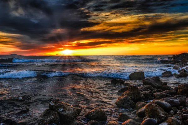Heller Sonnenuntergang unter dem Sturmmeer mit Wellenplätschern Stockbild