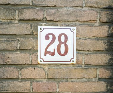 Ev numarası 28 yirmi sekiz. Eski bir tuğla duvar inşa beyaz bir plaka üzerinde kahverengi numaraları