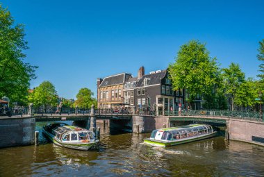 Amsterdam, 7 Mayıs 2018 - Prinsengracht ve Leidsegracht köşesinde güneşli bir günde kanallarda yelken turist tekneleri ile