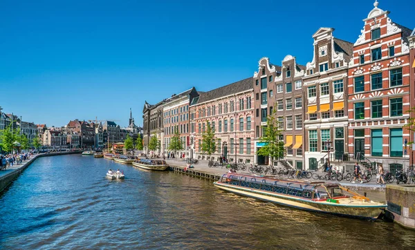 Amsterdam, 7 Mayıs 2018 - geleneksel evleri ve turist tekneleri ile Rokin Kanal