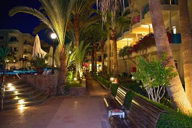 Banklar, palmiye ağaçları ve bir hoş resort aydınlatma - güvenli bir dinlenme ve romantik anlar için bir yer.