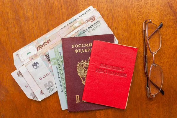 money, points and pension certificate on a wooden surface-translation into Russian: pensioner\'s certificate.
