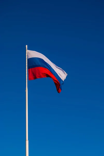 The national flag of Russia on the flagpole fluttering wind against the blue sky, Russia