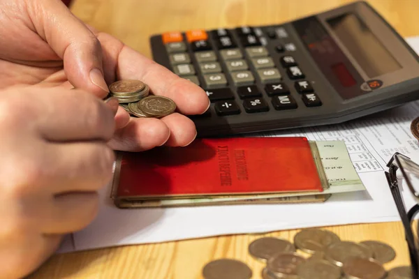 Hand pensioner, glasses, calculator and coins on the table surface. translation of the inscription - the identity of the pensioner