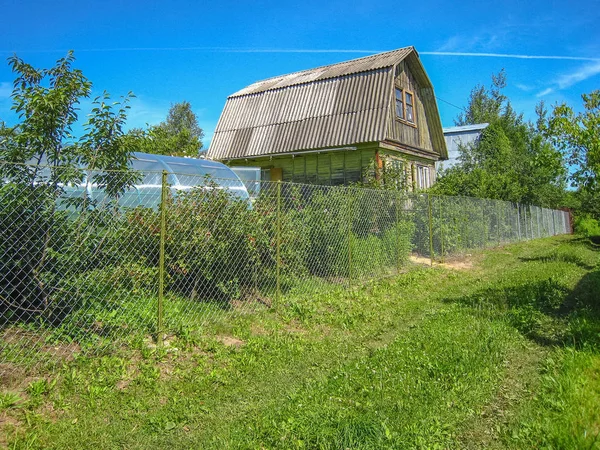 Small country wooden house, summer Sunny day fenced with mesh netting. Moscow Region, Russia