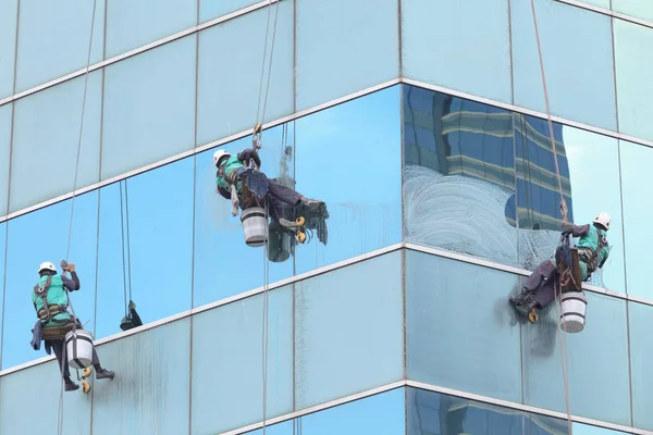 Grupo de trabalhadores serviço de limpeza de janelas em edifício alto — Fotografia de Stock