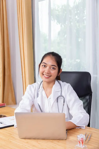 Een Vrouwelijke Dokter Glimlacht Terwijl Met Haar Computer Notebook Werkt — Stockfoto