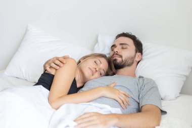 Genç ve tatlı çift yatakta sarılıp yatıyorlar.