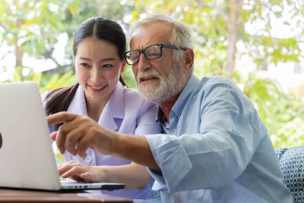 Nurse help senior retirement man working with laptop in the garden at home and feeling excited