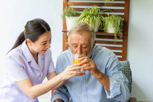 Krankenschwester Assistiert Seniorin Mit Einer Tasse Orangensaft — Stockfoto