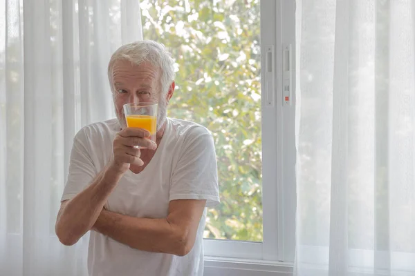 Rentner Steht Zimmerfenster Und Hält Ein Glas Orangensaft Der Hand — Stockfoto