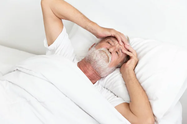 忧心忡忡的退休老人躺在床上醒着 — 图库照片