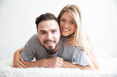 Yatakta bir çift kameraya bakar ve mutlu bir aşıkla gülümser.