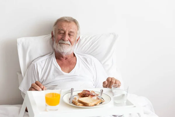 老年退休男性吃早餐 床上有橙汁和水 — 图库照片