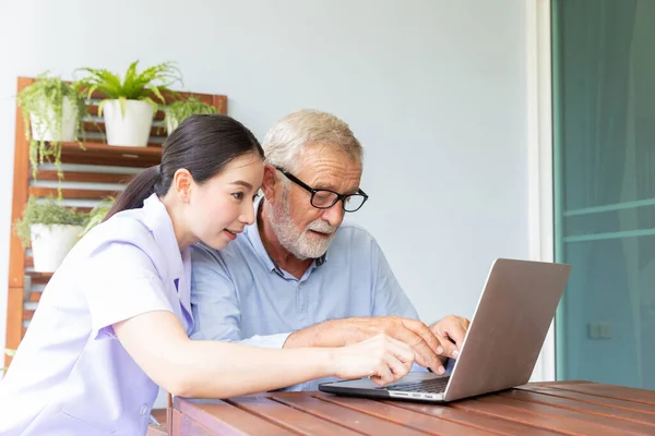 Nurse help senior retirement man working with laptop at home and feeling happy