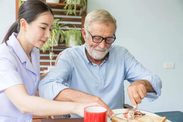 Verpleegster Assisteren Senior Man Samen Ontbijten — Stockfoto