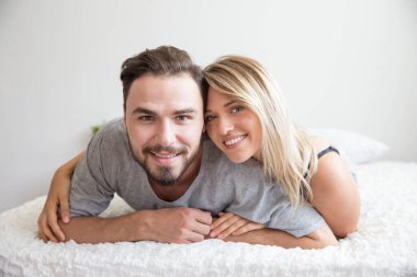 Yatakta bir çift kameraya bakar ve mutlu bir aşıkla gülümser.