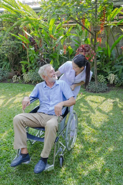 Bir Hemşire Evdeki Bahçesinde Tekerlekli Sandalyedeki Yaşlı Bir Erkeğe Bakıyor — Stok fotoğraf