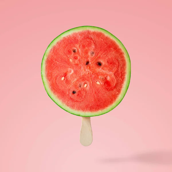 Watermelon with ice cream stick on pink background. Creative minimal concept.