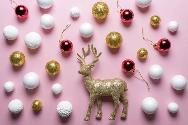 Gold glitter reindeer with gold, red and white glitter ball Christmas decoration on pink background. New Year minimal concept. Flat lay.