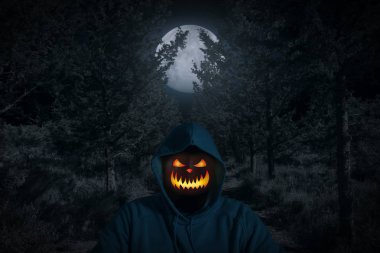 Balkabağına ayakta moon ile karanlık ormanın içinde hafif bir baş yerine bir adam portresi. Korku Cadılar Bayramı kavramı.