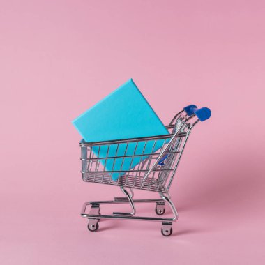 Pembe bir arka plan üzerinde alışveriş sepeti hediye kutuları. En az satış konsepti.