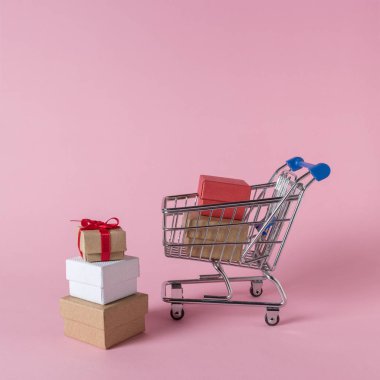 Pembe bir arka plan üzerinde alışveriş sepeti hediye kutuları. En az satış konsepti.