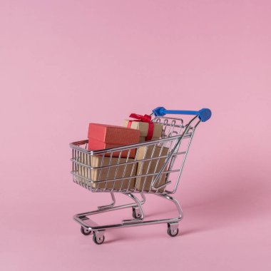 Pembe bir arka plan üzerinde alışveriş sepeti hediye kutuları. En az satış konsepti.