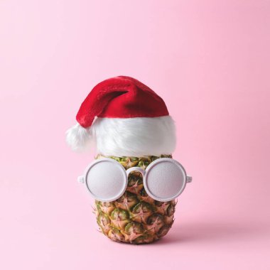 Noel Baba yüz üzerinden pineapple ve pembe bir arka plan üzerinde beyaz boyalı güneş gözlüğü yaptı. Noel en az kavramı.