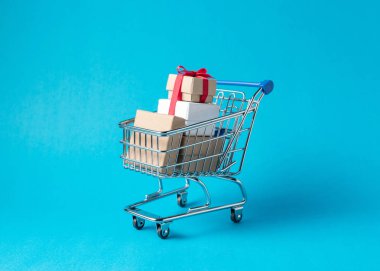 Mavi arka plan üzerinde alışveriş sepeti hediye kutuları. En az satış konsepti.