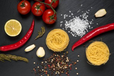 Renkli sebzeli erişte ve siyah arka planda baharatlar. Yiyecek konsepti.