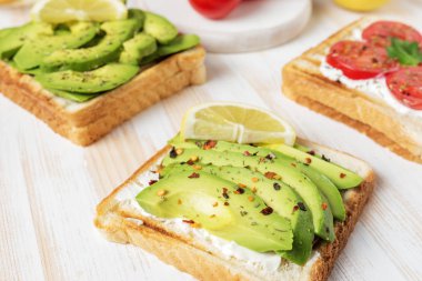 Tost ekmeği ile baharat beyaz ahşap zemin üzerinde üzerinde avokado dilimlenmiş. Gıda kavramı.