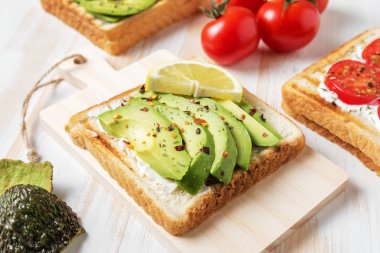 Tost ekmeği ile baharat beyaz ahşap zemin üzerinde üzerinde avokado dilimlenmiş. Gıda kavramı.