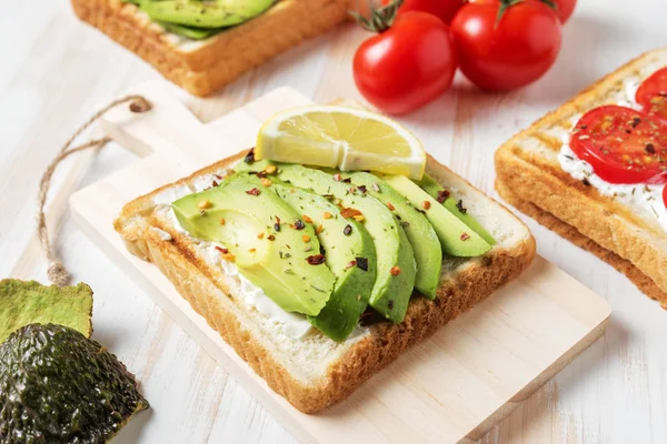 Tost ekmeği ile baharat beyaz ahşap zemin üzerinde üzerinde avokado dilimlenmiş. Gıda kavramı.