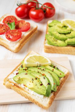 Tost ekmeği ile baharat beyaz ahşap zemin üzerinde üzerinde avokado dilimlenmiş. Gıda kavramı.