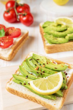 Tost ekmeği ile baharat beyaz ahşap zemin üzerinde üzerinde avokado dilimlenmiş. Gıda kavramı.