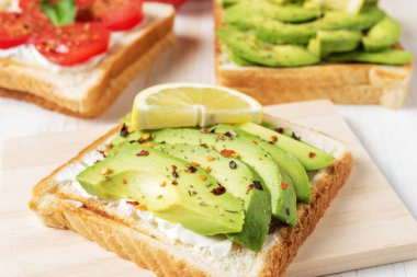 Tost ekmeği ile baharat beyaz ahşap zemin üzerinde üzerinde avokado dilimlenmiş. Gıda kavramı.